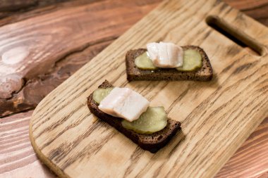 Tahta arka planda tereyağlı ve ringa balıklı siyah ekmekten yapılmış sandviç..