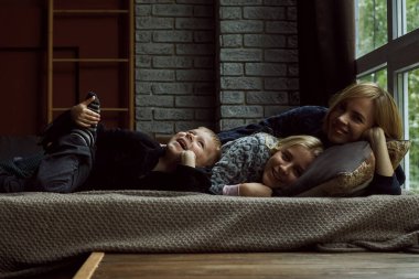 Yatakta çocuklu bir anne. Yanında bir erkek ve bir kız olan bir kadın pijamalarıyla yatıyorlar. Ebeveynlik kavramı, ilişki anne ve çocuklar.