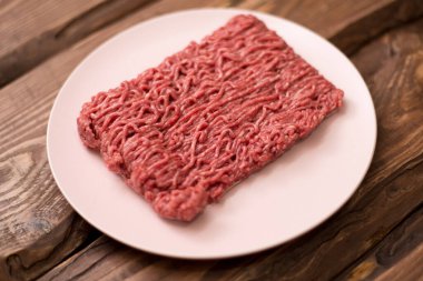 Ahşap bir arka planda, yemek pişirmek için taze kıyma..