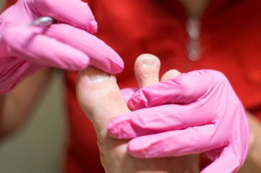 Erkek pedikür. Bir adamın ayağını tutan eldivenli bir pedikür ustası..