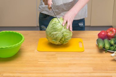 Bir kadın salata yapmak için lahana kafası kesiyor..