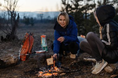 Anne, kızım piknikte ateşin yanında oturuyor. Seyahat, yürüyüş, konsepti durdurmak.