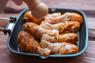 Sos içinde çiğ tavuk budu ve tavada baharat, ahşap arka plan değil..