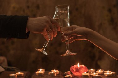 Şarap kadehleri olan kadın ve erkek. Mum ışığında romantik akşam yemeği.