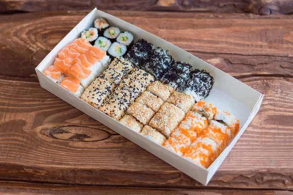 Sushi fast food in carton box on wooden background.