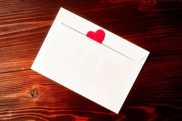 White envelope with a heart on a dark wooden background. Love letter, valentine concept.