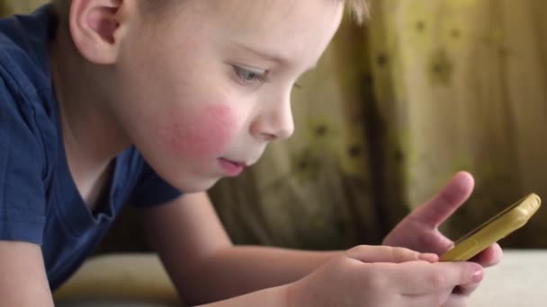 Niño Pequeño Mira Teléfono Mientras Está Acostado Sofá — Vídeo de stock