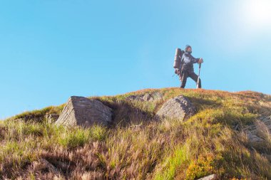 Sırt çantalı bir kadın dağlara tırmanıyor..