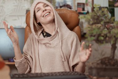 Neşeli bir kadın, mutluluktan elleri boşanmış bir şekilde oturur..