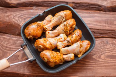 Sos içinde çiğ tavuk budu ve tavada baharat, ahşap arka plan değil..