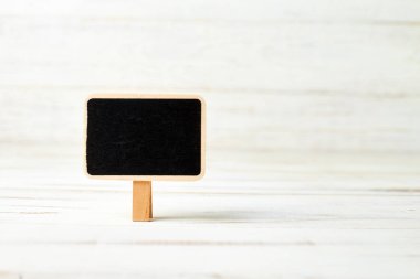 Beyaz ahşap arka planda küçük siyah bir poster. Yazıtlar için şablon.