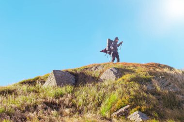 Sırt çantalı bir kadın dağlara tırmanıyor..