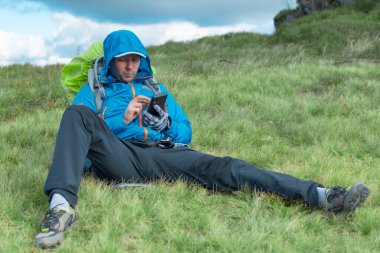 Karpaty, Ukrayna - 29 Eylül 2018: Bir erkek turist dağ gezisi sırasında elinde telefonla oturuyor.