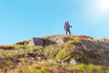 Sırt çantalı bir kadın dağlara tırmanıyor..