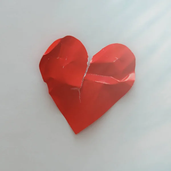 Torn heart on a light background. The concept of broken love, love suffering.