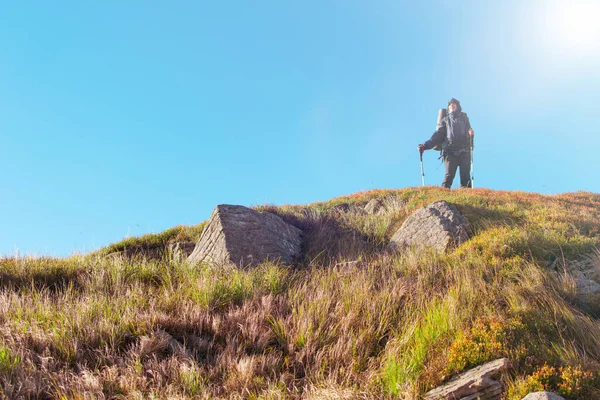 A woman with a backpack on a hike climbs the mountain.