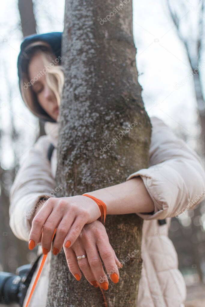 Restraint of women concept. A woman with her hands tied to a tree.