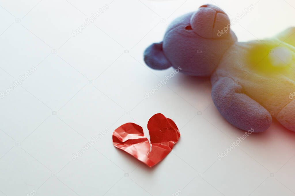 Damaged love heart and teddy bear. The concept of unrequited love, love suffering.