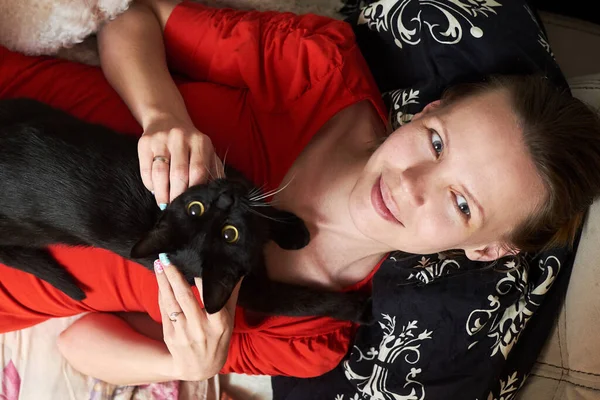 Een Vrouw Een Rode Jurk Ligt Bij Een Zwarte Kat — Stockfoto