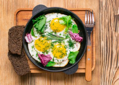 Kızartma tavasında yumurta ve yeşillik.