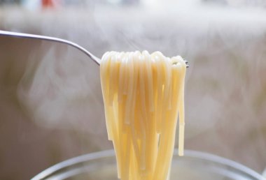 Tavanın arkasındaki çataldan sarkan haşlanmış spagetti. Spagettiden buhar çıkıyor..