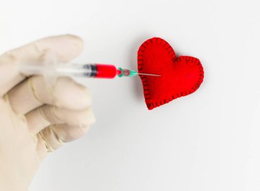 Kalbe bir aşk enjeksiyonu. Dikilmiş kalp ve şırınga, beyaz zemin üzerinde kırmızı sıvı var..