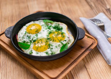 Kızartma tavasında yumurta ve yeşillik.