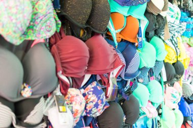 Bir sürü renkli kadın mayosu asılıyor. Çeşitli kadın kıyafetleri..