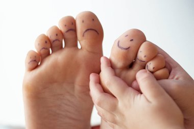Boyalı gülücükler ve çocuk eli olan kadın ayak parmakları. Ayak bakımı konsepti, pedikür.