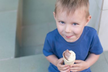 Küçük bir çocuk dondurma yiyor. Çocuk waffle bardağında limonlu çikolatalı dondurma yiyerek uzaklaşıyor. Bebek lezzeti..