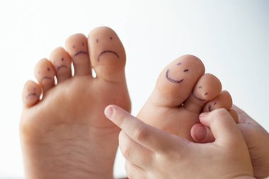 Boyalı gülücükler ve çocuk eli olan kadın ayak parmakları. Ayak bakımı konsepti, pedikür.