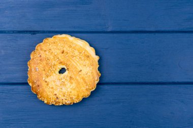 Mavi ahşap arka planda fındık serpiştirilmiş yuvarlak büyük kurabiyeler..