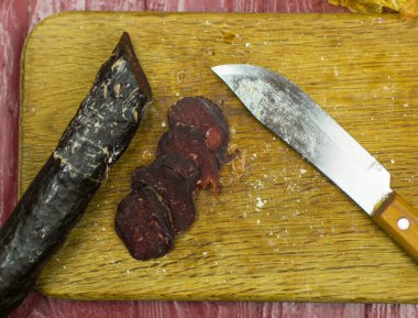 Koyu füme sosis (at eti) kesme tahtasının üzerinde kesilir.