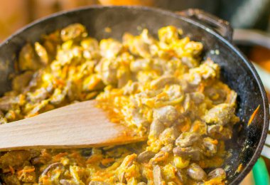 Kızartma tavasında soğan ve havuçla pişirilmiş tavuk kalbi..