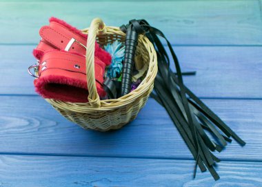 Kelepçe ve sepetteki BDSM için kırbaç. Cinsel oyunlar için aksesuarlar.