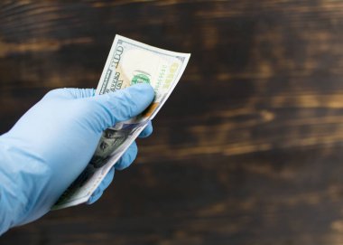 Kirli para. Lastik eldivendeki bir el 100 dolar tutar..