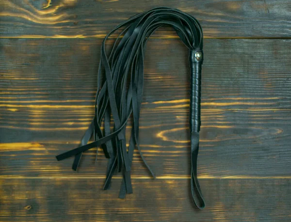 Koyu bir arka planda BDSM için kırbaç. Cinsel oyunlar için suç ortağı.