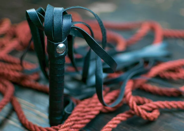 Kölelik için kırbaç ve karanlık bir arka plan için ip. Cinsel oyunlar için aksesuarlar.