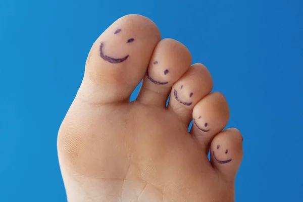 Female toes with painted smileys.