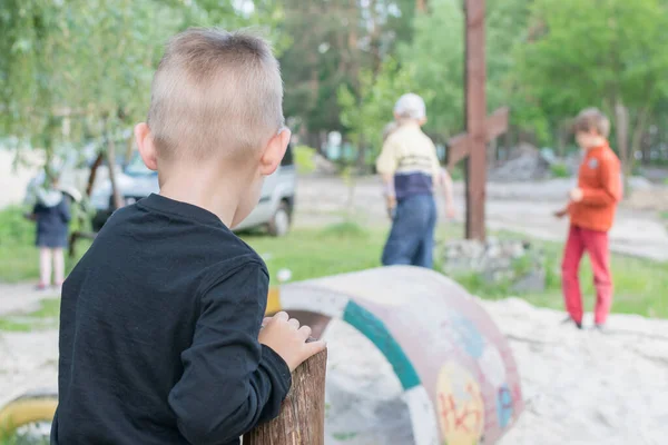 Yalnızlık, çocuğu terk etmek gibi. Küçük bir çocuk diğer çocukların oyununa bakıyor. Arkadan bak..