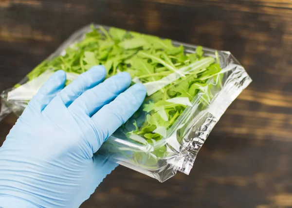 Kauçuk eldivenli bir pakette roka salatası..