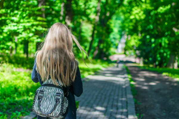 Genç bir kadın yazın parkta yürüyor.