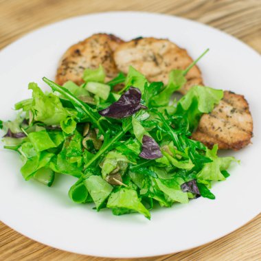 Yaprak salatası ve ahşap arka planda ızgara et..