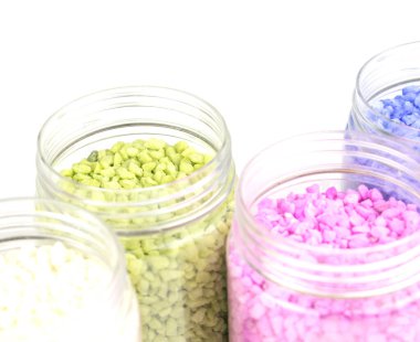 Kavanozlarda beyaz arkaplanda çok renkli taşlar..