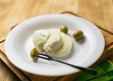 Peynirli mozzarella ve ahşap arka planda bir tabakta zeytin..