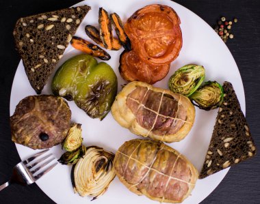 Beyaz tabakta ızgara sebzeli pirzola ve siyah bir arka plan..