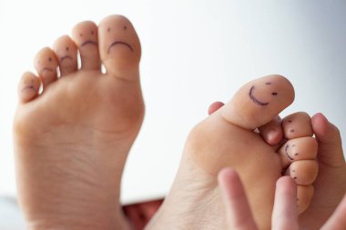 Boyalı gülücükler ve çocuk eli olan kadın ayak parmakları. Ayak bakımı konsepti, pedikür.