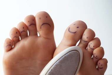Boyalı gülücükler ve pedikür rendesi olan kadın ayak parmakları. Ayak bakımı kavramı.