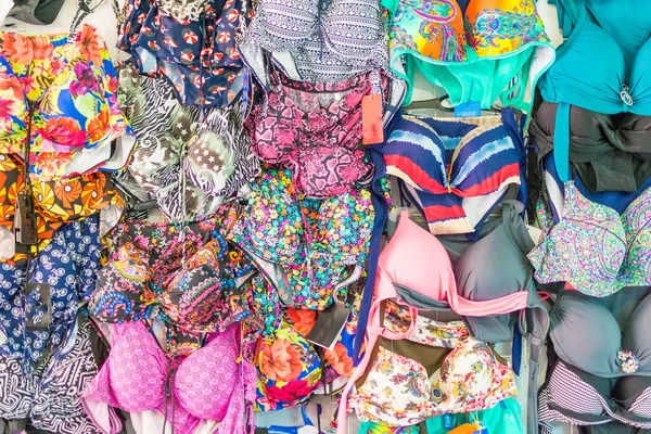 Bir sürü renkli kadın mayosu asılıyor. Çeşitli kadın kıyafetleri..