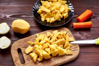 Tahtada dilimlenmiş çiğ patates. Pişirmek için sebze hazırlıyorum..